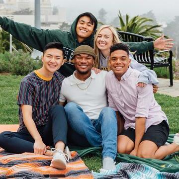 五个学生坐在野餐毯子上